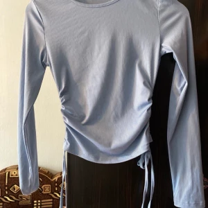 Ljusblå långärmad topp med knyt - Säljer en superfin ljusblå topp med långa ärmar och knyt i sidorna. Perfekt för både vardag och fest! Den har en smickrande passform och är gjord i ett mjukt och bekvämt material. Passar perfekt till jeans eller kjol. Hör av dig vid intresse! 💙