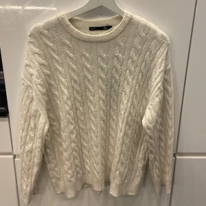 Vit stickad tröja  - Mysig vit stickad tröja från lager 157 i storlek S. Perfekt för kalla dagar med sitt klassiska flätmönster och långa ärmar. Tröjan är i nyskick och passar både till vardags och lite finare tillfällen. Superbekväm och stilren!🐑