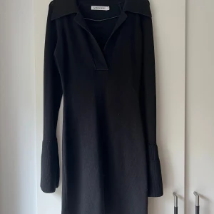 Adoore Day-to-night-dress Black - Svart klänning med långa ärmar och krage. Klänningen är figursydd och har en lätt trumpetvidd vid ärmsluten. Stretchigt material. Klänningen är endast använd två gånger så den är som ny.  