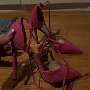 Rosa mocka pumps med snörning - Säljer ett par snygga rosa pumps i mocka med spetsig tå och hög klack. Skorna har en elegant snörning som kan knytas på många olika sätt. Aldrig använda! 