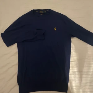 Stickad Ralph Lauren tröja - Fet mörkblå ralph lauren tröja med gul logga. Storleken är M men sitter som S. Skick 9/10 knappt använd. Skriv vid funderingar!