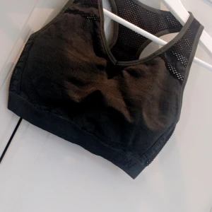 Svart sport-bh - Säljer en Mörkgrön sport-bh i syntetmaterial. Den har en tight passform och är perfekt för träning. Designen är enkel men funktionell med meshdetaljer för extra ventilation. Perfekt för gymmet eller löprundan!