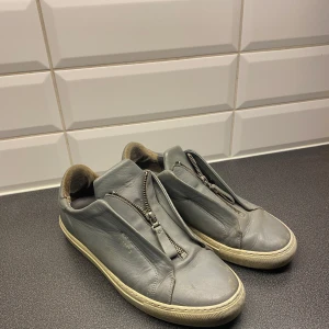 Axel arigatos skor - Gråa arigatos med kedja. Billigare vid snabb affär. Riktigt sköna och clean. Inge mycket skador, sulan är lite sliten men inga hål. Vid frågor eller mer skicka meddelande, svarar så fort jag kan.