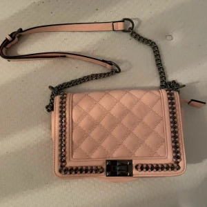 Rosa quiltad axelväska - Säljer en superfin rosa axelväska med quiltat mönster och snygga kedjedetaljer. Väskan har en justerbar axelrem och ett praktiskt innerfack. Perfekt för både vardag och fest! 💖aldrig använd 