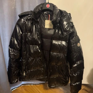 Svart Moncler Maya - Säljer min moncler maya då jag tröttnat o vill köpa ny, den är använd och har en liten skada som kan ses på sista bilden. 