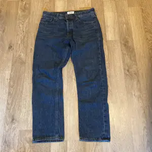 Säljer ett par snygga blå jeans från Jack & Jones i modellen Loose/Chris. De har en avslappnad passform och är perfekta för en casual look. Storlek 30:30. Jeansen är i bra skick och har klassiska fem fickor samt en knappgylf. Perfekta för både vardag och fest!