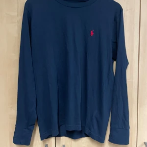 Mörkblå långärmad tröja - Säljer en snygg mörkblå långärmad tröja från Polo Ralph Lauren. Tröjan är i bra skick men använd. 