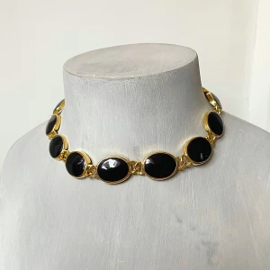 Svart och guld chokerhalsband - Snyggt chokerhalsband med svarta ovala stenar infattade i guldfärgad metall. Perfekt för att ge en elegant touch till din outfit. Passar både till fest och vardag!