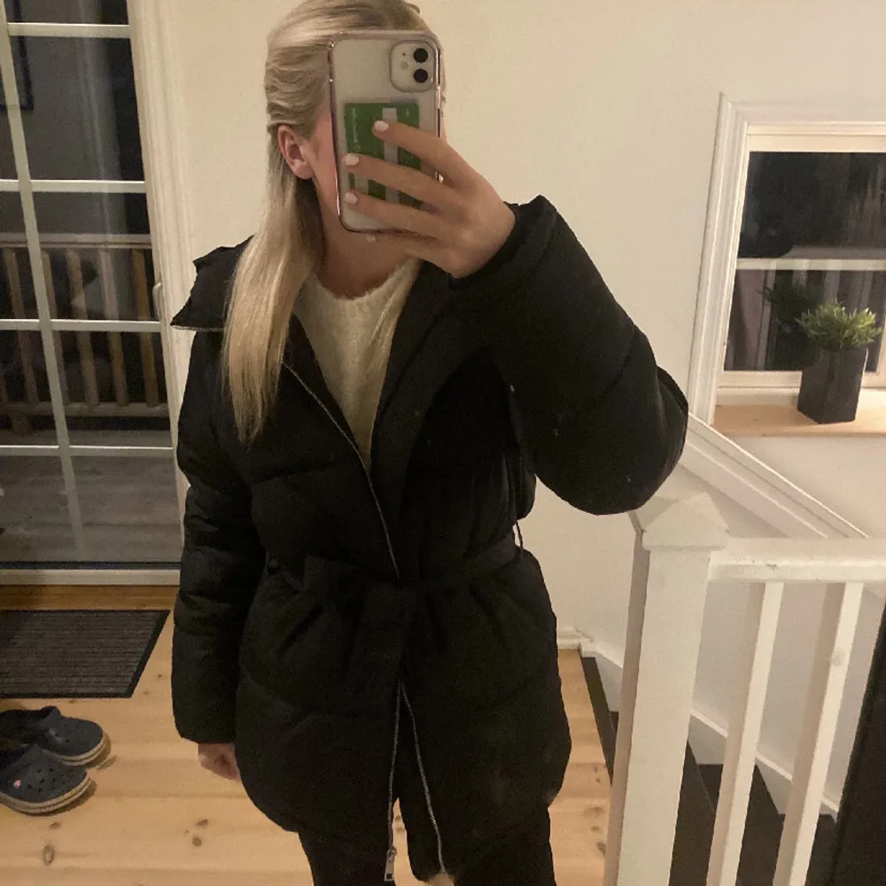 Säljer en snygg svart pufferjacka som är perfekt för kalla dagar. Den har en dragkedja framtill och ett bälte i midjan för en fin passform. Jackan är långärmad och supermysig att ha på sig. Perfekt för både höst och vinter!. Takit.