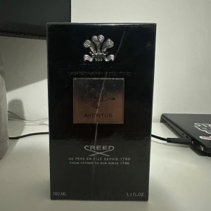 Creed Aventus Parfym - Säljer en lyxig och elegant parfym från Creed, modellen Aventus. Flaskan är på 100 ml och kommer i en stilren svart förpackning med silverdetaljer. Creed är kända för sina exklusiva dofter och denna är inget undantag. Perfekt för den som vill ha en sofistikerad och tidlös doft.