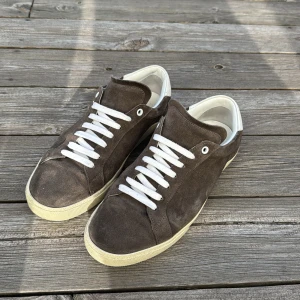 Saint Laurent skor - Säljer dessa populära SL/06 skor från Saint Laurent / Skorna är i bra skick, använda men utan några flaws / Size: 42 / Endast skorna följer med vid köp / Färgen på skorna är brun/grå / Nypris~ 7000kr, mitt pris: 2499kr / Hör av er vid funderingar!