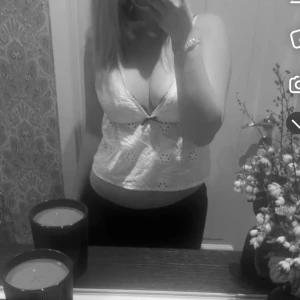 Vit spetslinne - Säljer en söt vit spetslinne med broderade detaljer. Den är ärmlös och har en djup v-ringning, perfekt för sommardagar eller en festlig kväll. Toppen är croppad och ger en luftig och lätt känsla.