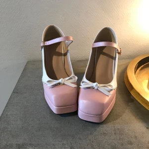 Cutesy Klackar - 10cm höga klackar, med en liten rosa rosett och vit/rosa färg. De är använda en gång men har inga tecken på användning. Kan skickas mot portokostnad:) 