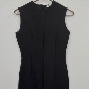 Svart ärmlös klänning - Säljer en elegant svart ärmlös klänning. Klänningen har en dragkedja i ryggen. Tjockt material men jättefin textur som ger en extra touch av stil. Perfekt för både höst och vinter! Endast använd en gång💕