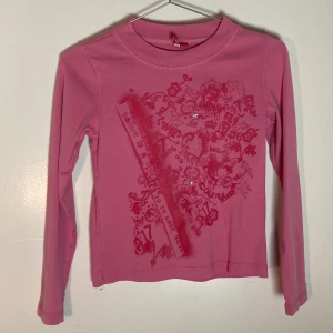 Rosa långärmad tröja coolt tryck och bling - Fin rosa långärmad tröja med triballiknande galet tryck och bling stjärnor.   Liten i storleken och passar xxs-xs beroende på hur tajt