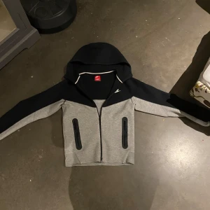 Nike tech - Nike tech, en varm och kön zip hoodie till vintern när det är kallt, den har inga skador eller något köpte den förra veckan för 1300kr men den var för liten därför säljer jag den vidare. Kan ta byten!