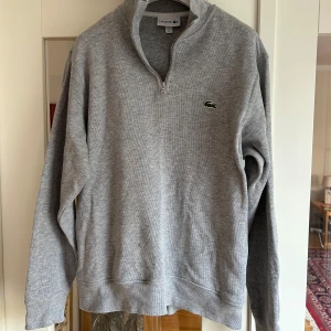 Lacoste Rib Interlock Half Zip Grå - US Large. Använd 4-5 gånger (alltså i perfekt skick) Jag är 188cm och den sitter bra på mig. Nypris: 1599:-