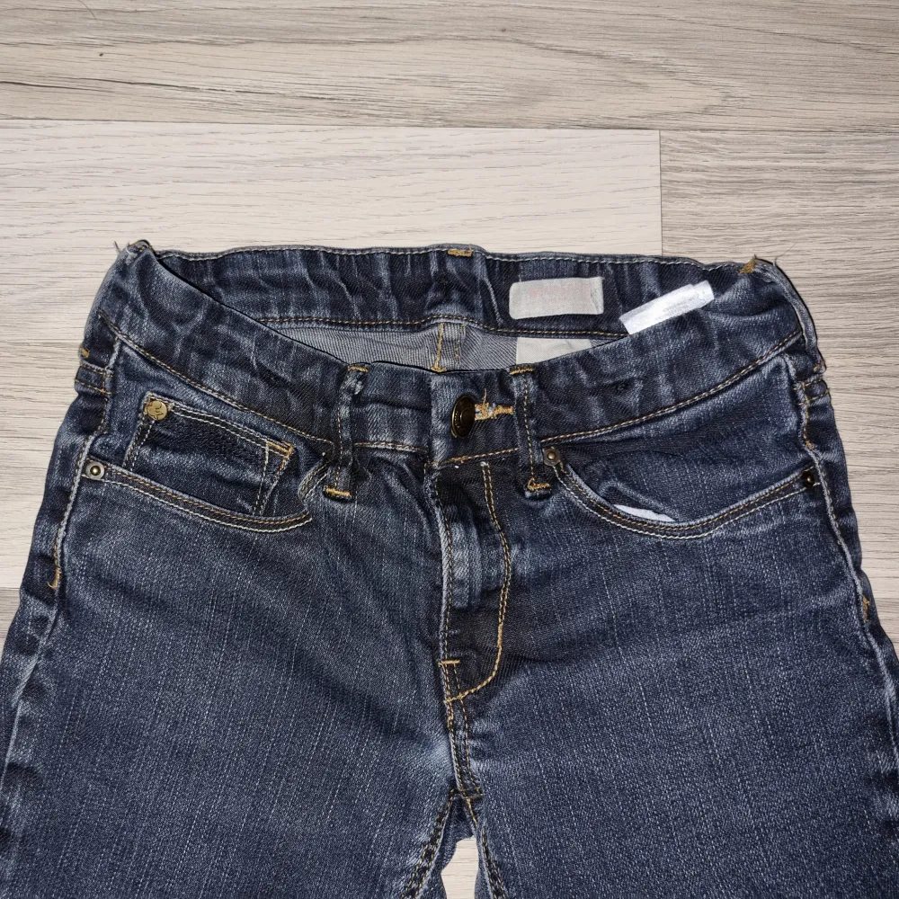 Säljer ett par mörkblå jeans i nyskick. De har en snygg slim passform. Jeansen har coola dragkedjedetaljer på bakfickorna och en elastisk midja för extra komfort. Från H&M i stl 134.. Jeans & Byxor.