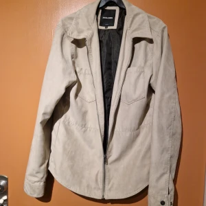 Beige jacka från Jack & Jones - Säljer en snygg beige jacka från Jack & Jones i storlek M. Jackan har en dragkedja framtill och är i mycket bra skick. Perfekt för höst och vår med sin stilrena design och bekväma passform. Passar både till vardags och lite finare tillfällen.