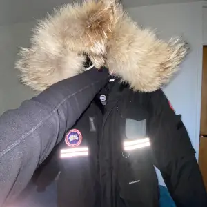 Säljer en svart vinterjacka från Snow Mantra i mycket bra skick. Jackan har en stor, fluffig pälsfodrad huva och är perfekt för kalla vinterdagar. Den har långa ärmar och flera praktiska fickor. Reflekterande detaljer ger extra synlighet. Perfekt för dig som vill hålla dig varm och snygg i vinter! ❄️