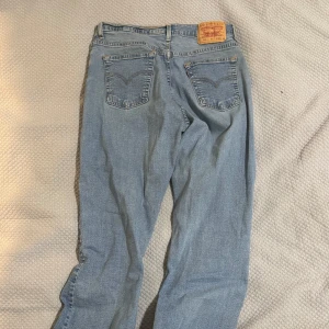 Levis 504 ljusblå jeans - Säljer ett par klassiska Levis 504 jeans i ljusblå denim. De har en rak passform och är i okej skick. Perfekta för en avslappnad stil och funkar året runt. Har knappgylf och fem fickor. Passar både till vardags och fest!