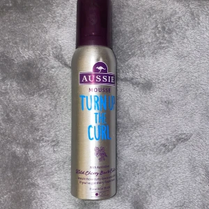 Aussie Mousse Turn Up The Curl - Helt ny Aussie Mousse Turn Up The Curl är en hårmousse med Australian Wild Cherry Bark Extract. Perfekt för att definiera lockar och ge dem extra studs och glans. Den kommer i en silverfärgad flaska med lila detaljer och har en flexibel hållbarhet. Perfekt för dig som vill ha mjuka och definierade lockar utan att håret känns stelt.