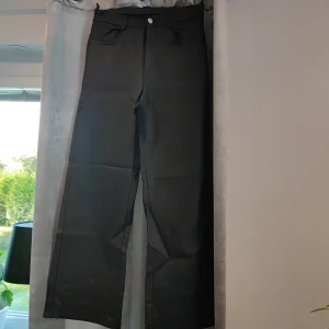 Svarta vida byxor - Säljer ett par snygga svarta byxor i mycket bra skick. De är högmidjade och har en loose fit med vida ben, perfekt för både vardag och fest. Byxorna har knappar och dragkedja framtill samt fickor både fram och bak. Materialet känns slitstarkt och bekvämt. Passar perfekt till höst- och vintergarderoben!