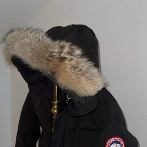 Säljer en svart parkajacka från Canada Goose i mycket bra skick. Jackan har en stor huva med pälsdetaljer och är perfekt för kalla vinterdagar. Den har en dragkedja framtill och är långärmad. Supervarm och stilren, perfekt för både stad och natur! 🖤Canada Goose, Carson Parka. Storlek Xs-S, Digitalt kvitto medföljs! Köpt på Johnells!