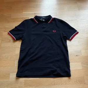 Svart pikétröja från Fred Perry - Mörkblå/svart pikétröja från Fred Perry i helt nytt skick i storlek S. Riktigt bra passande, köpt för 900kr