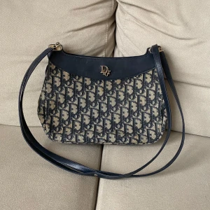 Vintage Christian Dior väska  - Äkta vintage Christian Dior montaigne navy axelremsväska i gott skick. Inga sprickor i läder eller revor i tyget.  Mått: Ca 19 cm hög, 25 cm bred. Ca 75 cm Längd på axelrem.