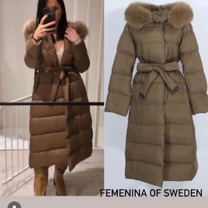 Brun dunjacka från Femina of Sweden - Säljer en supermysig brun dunjacka från Femina of Sweden. Den är lång och har en fluffig pälskrage som är perfekt för kalla vinterdagar. Jackan har ett bälte i midjan för en snygg siluett och knappar framtill. Perfekt för att hålla sig varm och stilren under vintern! Ny pris 3799kr 