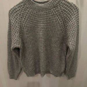 Grå stickad tröja från 157 - Mysig grå stickad tröja från 157 i storlek S. Perfekt för kyliga dagar med sin varma och bekväma design. Tröjan har långa ärmar och en klassisk rund halsringning. Passar både till vardags och för mysiga hemmakvällar. 🧶