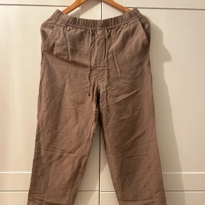 Bruna linnebyxor - Säljer ett par bekväma bruna linnebyxor med elastisk midja. Perfekta för en avslappnad stil och passar bra till både vardag och sommarhäng. Byxorna har en loose passform som ger en skön känsla hela dagen. Använt fåtal gånger. Köpt för 300kr
