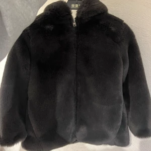 Svart pälsjacka med huva - Mysig mörk grå pälsjacka från Zara i mycket bra skick. Den har världens fluffigaste o mysiga päls, jackan är varm och passar till höst och vinter. Både jättesnygg och mysig! Använd ett fåtal gånger, jackan ser ut o vara i nyskick! Säljer då den är för liten.