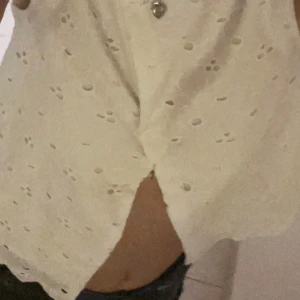 Vit ärmlös topp med broderade detaljer. - Säljer en söt vit ärmlös topp med fina broderade blommor. Toppen har en omlott-design framtill och är perfekt för sommardagar. Den är i bra skick och passar till både jeans och kjol. Funkar att ha åt två håll. Storlek xs 