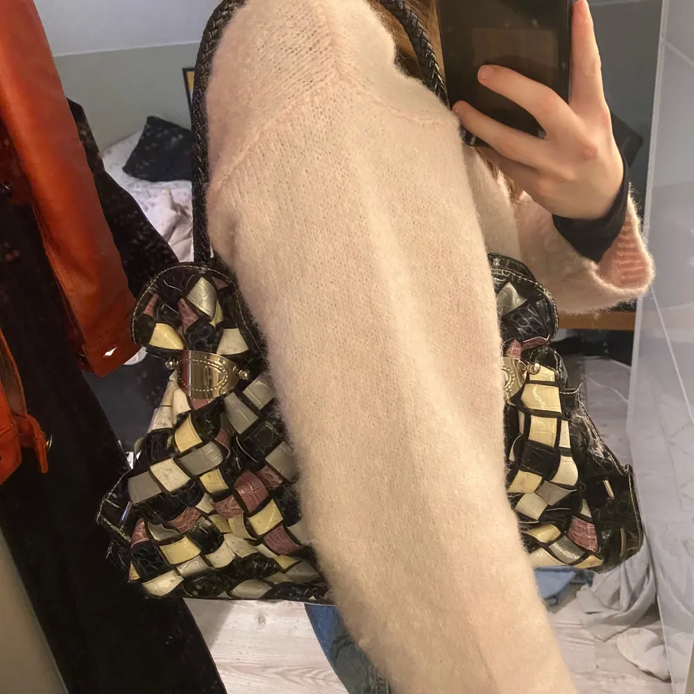 Säljer en unik axelväska med ett coolt rutigt mönster i svart, vit, lila och beige. Väskan har en glansig finish och är gjord av syntetmaterial. Perfekt för att ge din outfit en färgglad touch! 👜💐🌟. Laukut & Käsilaukut.