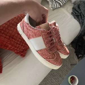 Glittriga sneakers från Valentino - Säljer ett par supercoola glittriga sneakers från Valentino i rosa och vitt. De har en snygg glittrig yta med vita detaljer och rosa snörning. Köpta förra veckan men säljer då de var för små🩷Skorna är i nyskick förutom att två nitar har åkt bort på ena skon, men inget man tänker på. Skorna kommer med box, dustbag, orginalsnören. Tveka inte på att höra av er! Pris går att diskutera vid snabb affär!! Säljer direkt för 2300