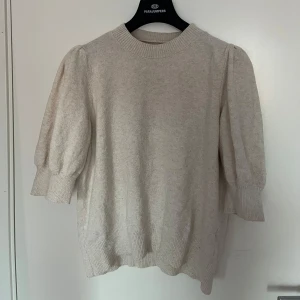 Beige stickad tröja - Mysig beige stickad tröja med puffiga trekvartsärmar och ribbade muddar. Perfekt för höst och vår, den är både stilren och bekväm. Passar bra till både jeans och kjol för en avslappnad look.