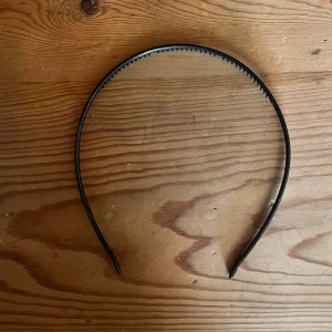 Svart diadem - Säljer ett enkelt och stilrent svart diadem. Perfekt för att hålla håret på plats eller som en snygg accessoar till vardags och fest. Det är i bra skick och passar de flesta huvudstorlekar.