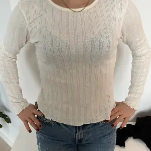 Säljer en superfin vit ribbad topp med långa ärmar. Den har ett subtilt mönster och är perfekt för både vardag och fest. Toppen är i mycket bra skick och passar perfekt till jeans eller kjol. Perfekt för vår och sommar!