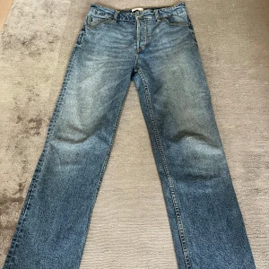 Blå jeans från HM - Säljer ett par klassiska blå jeans från HM. De har en straight passform och är i bra skick. Perfekta för vardagsbruk med knappgylf och femficksdesign. Passar till alla tillfällen!