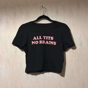 Säljer en svart t-shirt med korta ärmar och rosa text 'ALL TITS NO BRAINS' på framsidan. Perfekt för en avslappnad stil med en touch av humor. Passar bra till jeans eller kjol för en cool look. Porto 58:- som köparen står för, jag tar betalt via Swish direkt vid köp och skickar sen.