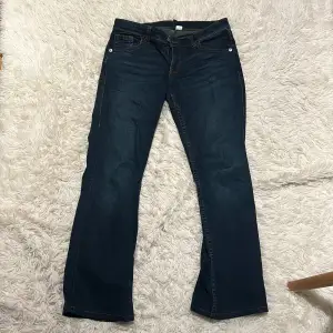 Säljer ett par snygga mörkblå bootcut jeans i bra skick. De har en klassisk femficksdesign med snygga sömmar på bakfickan, från HM