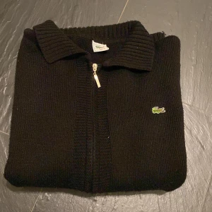 Lacoste ziptröja - Relativt bra skick, finns lite defekter vid armen men annars inget fel. Kom gärna med bud och tveka ej vid frågor.