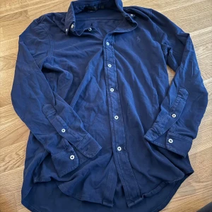 Blå skjorta från Ralph Lauren - Säljer en snygg blå långärmad skjorta från Ralph Lauren i storlek S. Skjortan är i bomull och har klassiska knappar framtill. Perfekt för både vardag och festliga tillfällen. Den har en broderad logga på bröstet som ger en stilren touch. Passar perfekt till jeans eller chinos!