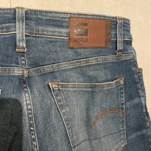 Blå jeans från G-Star RAW - WIDTH: 30 LENGHT: 32 Säljer ett par snygga blå jeans från G-Star RAW. De har en klassisk femficksdesign och en bekväm passform. Jeansen har en lätt tvättad look med subtila slitningar för en trendig stil. 