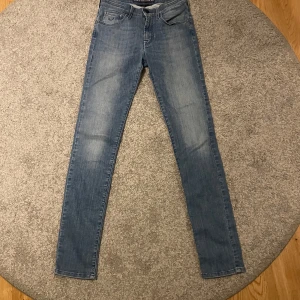 Blå jeans från Jacob Cohën - Säljer ett par snygga blå jeans från Jacob Cohën. De är handgjorda och har en lyxig känsla. Jeansen har en tight passform och är perfekta för både vardag och fest. Märkesdetaljer finns på baksidan och insidan av midjan. Passar perfekt för dig som vill ha stil och komfort i ett!