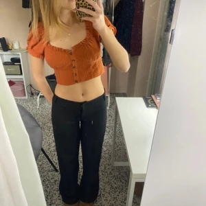 Orange topp - Säljer en supersöt orange topp med knappar framtill. Den är kortare och har en snygg passform som är perfekt för sommaren. Perfekt för både vardag och fest! 🩷