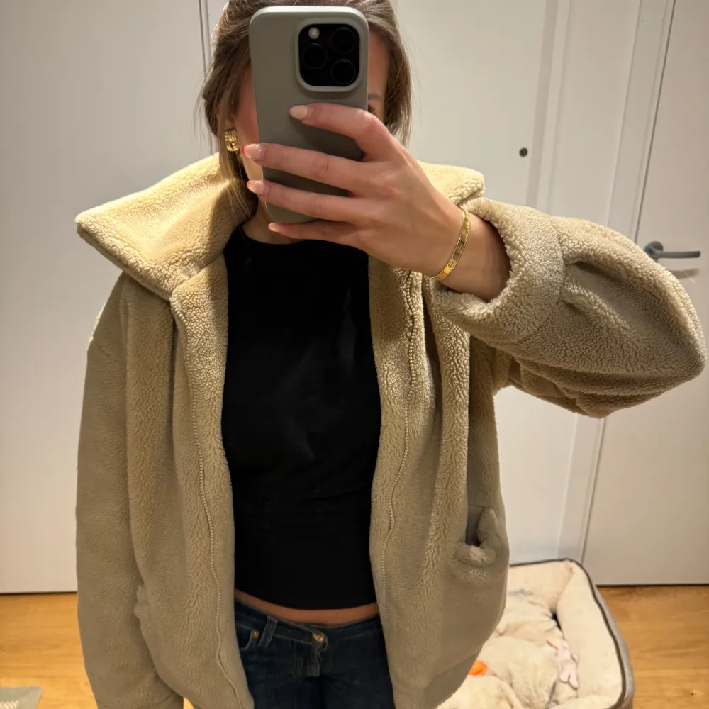 Mysig beige teddyjacka från NAKD i oversized stil. Perfekt för höst och vinter med sin fluffiga och varma design. Jackan har långa ärmar och en hög krage som skyddar mot kylan. Den är i mycket bra skick💕. Jackor.