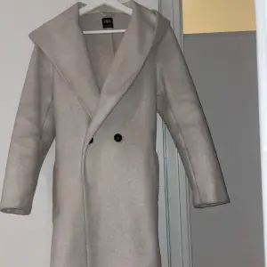 Säljer en elegant beige kappa från Zara. Den har en stilren design med knappar framtill och ett bälte i midjan för en snygg passform. Perfekt för höst och vår, med långa ärmar och en klassisk huva. Passar både till vardags och festliga tillfällen. Storlek xs men passar även bra om du ha S.